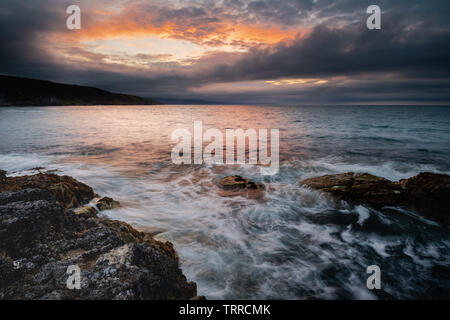 Portmuck, Islandmagee, comté d'Antrim, en Irlande du Nord : un coucher de soleil et la formation de nuages créer l'apparence d'un trou dans le ciel Banque D'Images