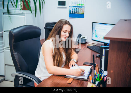 Young caucasian business femme assise sur son lieu de travail en bureau. L'entrepreneuriat féminin. Portrait de main manager satisfait de l'occupation. Séle Banque D'Images