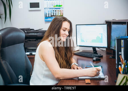 Young caucasian business femme assise sur son lieu de travail en bureau. L'entrepreneuriat féminin. Portrait de main manager satisfait de l'occupation. Séle Banque D'Images