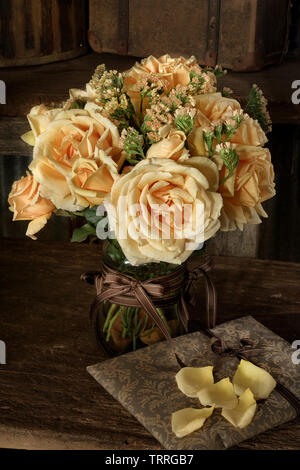 Fenêtre naturelle de la lumière sur un petit bouquet de roses Valence et Statice. Photographié sur un banc en bois rustique. Banque D'Images