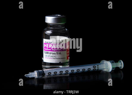 Une bouteille de l'anticoagulant Héparine sodique avec une seringue sur un fond noir Banque D'Images