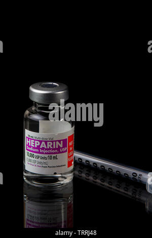 Une bouteille de l'anticoagulant Héparine sodique avec une seringue sur un fond noir Banque D'Images