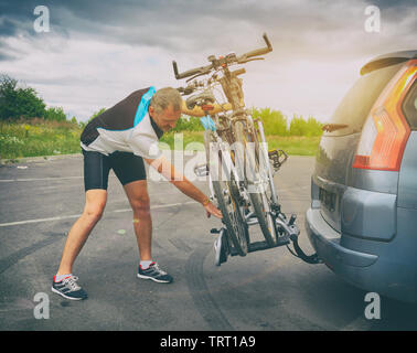 Homme portant des vêtements de sport sur le chargement des vélos porte vélo monté sur un attelage de voiture Banque D'Images