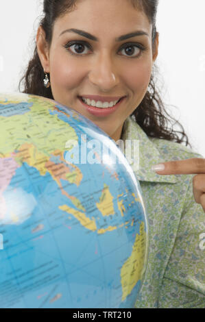 Portrait d'une jeune femme Indienne dirigée vers un globe de bureau Banque D'Images