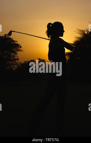 Silhouette of a woman playing golf Stock Photo