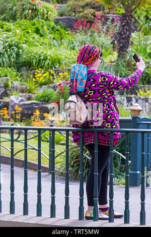 Femme dans la prise de raccordement colorés en selfies Jardins de Bournemouth à Bournemouth, Dorset UK en Juin Banque D'Images