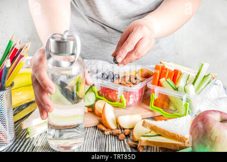 École de cuisine mère lunch box set, la préparation de collations santé - cheese sandwich au concombre, carotte. des noix, des fruits et légumes en boîte. Banque D'Images