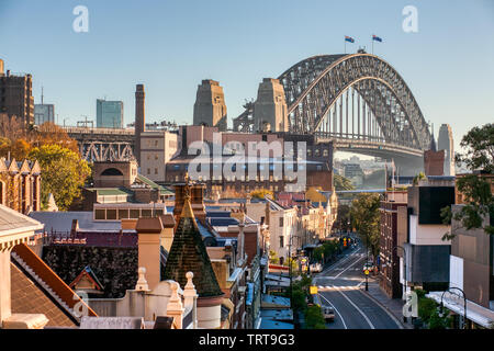 The Rocks, Sydney, George Street, Sydney Harbour Bridge et les bâtiments avec ciel bleu. Célèbre Centre-ville historique de rue. Matin ensoleillé. Banque D'Images