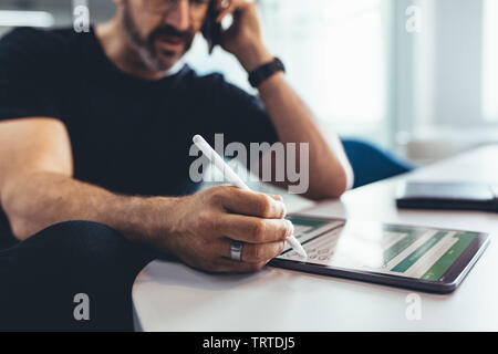 Businessman working on laptop et parlant au téléphone. Entrepreneur masculin contrôle des rapports financiers sur sa tablette ordinateur et parlant au téléphone. Banque D'Images