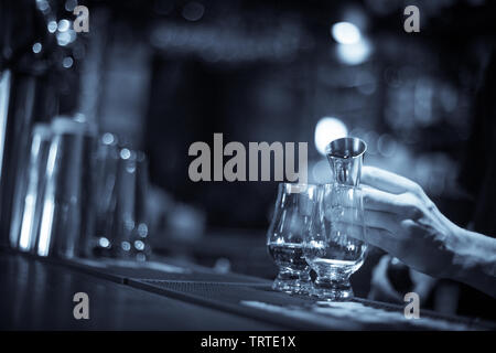 Gros plan d'un bartender pouring dans un verre de whisky Glencairn. Banque D'Images