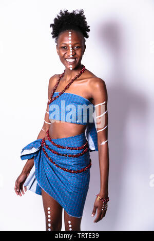 Jeune fille africaine peint avec motif dans des points et spirales en bleu jupe et top rire dans studio Banque D'Images