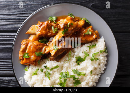 Côte de boeuf dans une sauce épicée avec du riz garnir close-up sur une plaque sur la table. haut horizontale Vue de dessus Banque D'Images