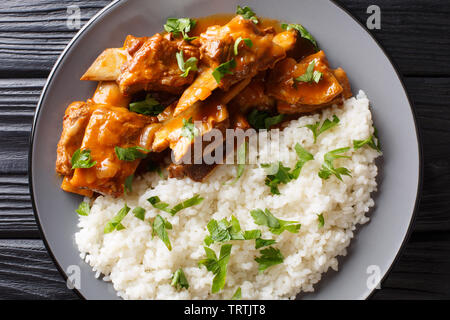 Délicieux ragoût de côtes dans une sauce épicée servis avec du riz blanc gros plan sur une assiette sur la table. haut horizontale Vue de dessus Banque D'Images