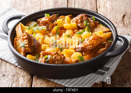 Ragoût de boeuf servi avec des pommes de côtes courtes dans une sauce épicée, libre dans un pot sur la table horizontale. Banque D'Images