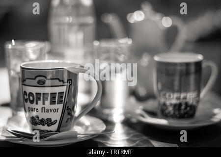 Deux tasses de café et de verres d'eau dans la taverne grecque exposée passant au flou d'extrême Banque D'Images