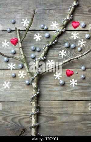 Concept d'arbre de Noël avec des branches d'arbres sans feuilles, flocons de neige, coeur rouge, d'argent et les globules de chaîne de perles sur fond de bois Banque D'Images