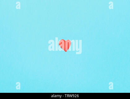 Un petit coeur coupé de papier rouge sur fond de papier pastel turquoise bleu Banque D'Images