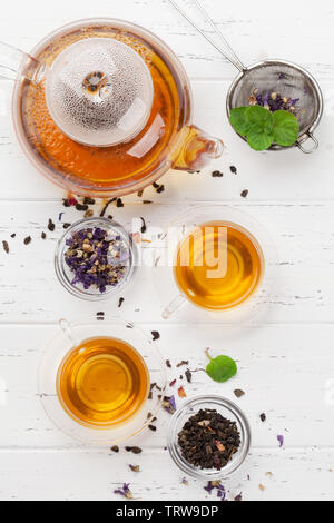 De fines herbes et de fruits différents thés à sec, Théière et tasses sur la table en bois. Vue supérieure mise à plat Banque D'Images