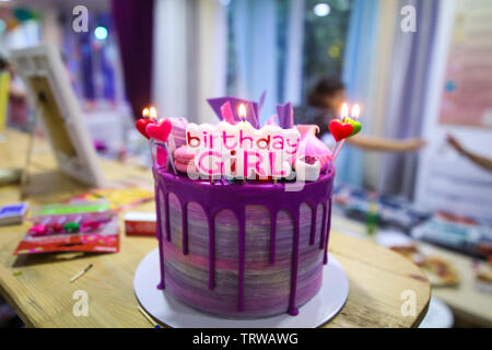 Gâteau d'anniversaire coloré avec le message anniversaire fille et allumé des bougies sur elle Banque D'Images