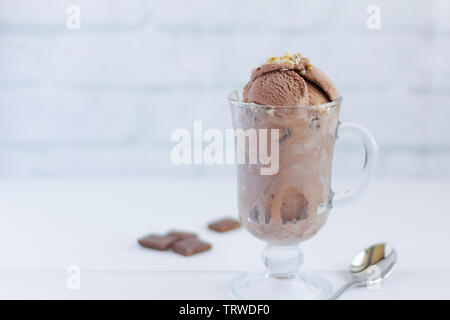 Glace au chocolat aux noix et sauce aux canneberges dans un verre sur un fond clair Banque D'Images