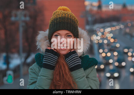 Beau portrait de jeune femme d'hiver en hiver paysage enneigé. Jolie fille aux cheveux roux marche sur une soirée d'hiver ville Banque D'Images