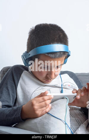 Jeune garçon, 11-12 ans, regarde des vidéos en ligne sur son téléphone intelligent Banque D'Images