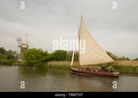 Trois hommes dans un bateau à voile sur la rivière à Ant en face de Turf Drainage Fen Moulin, comment Hill, Norfolk Broads, UK, Mai Banque D'Images