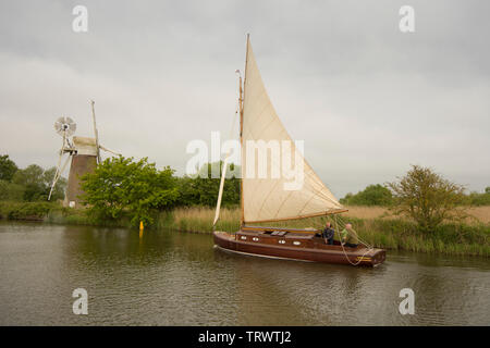 Trois hommes dans un bateau à voile sur la rivière à Ant en face de Turf Drainage Fen Moulin, comment Hill, Norfolk Broads, UK, Mai Banque D'Images