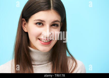 Tête et épaule portrait of a young woman isolé sur fond bleu Banque D'Images