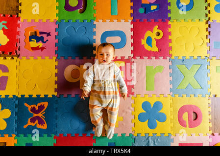 Adorable smiling baby vu de dessus en pyjama, couché sur le dos dans son jouet prix. Banque D'Images