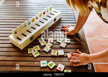 Mains d'un enfant à l'aide d'un jouet en bois pour comparer des images, utilisés dans les pédagogies alternatives, dans l'arrière-cour de sa maison. Banque D'Images