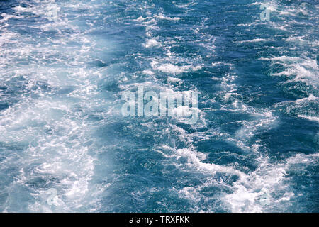 Faites par la turbulence de l'eau de mer de mousse d'un yacht à grande vitesse sur la surface de la mer. Les vagues de la mer bleue avec beaucoup d'écume de mer. Surface de mer avec les vagues. Banque D'Images
