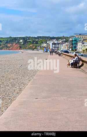 Afficher le long de la promenade surplombant la plage de galets à Seaton dans Jurassic Coast.Devon cliffs à distance. Des gens assis et d'autres se promener le long. Banque D'Images