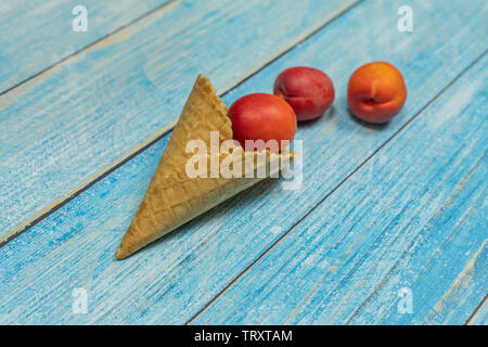 Saison des fruits. La crème glacée aux fruits. Abricot dans une gaufre sur un fond en bois bleu. Banque D'Images