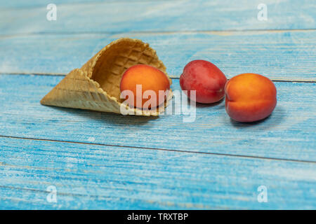 Saison des fruits. La crème glacée aux fruits. Abricot dans une gaufre sur un fond en bois bleu. Banque D'Images