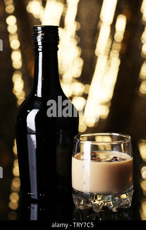 Liqueur Baileys en bouteille et verre sur fond doré Banque D'Images