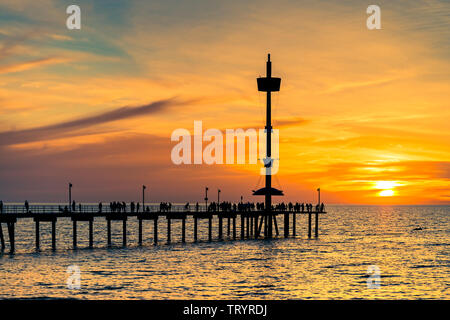 Les gens silhouettes sur la jetée de Brighton et bateau moderne au coucher du soleil, dans le sud de l'Australie Banque D'Images