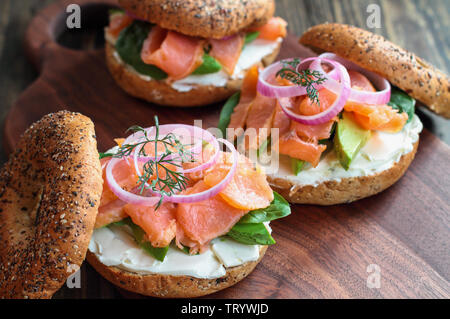 Lox - Tout ce bagel avec du saumon fumé, Épinards, oignons rouges, avocat et fromage à la crème sur une table en bois rustique. Focus sélectif. Banque D'Images