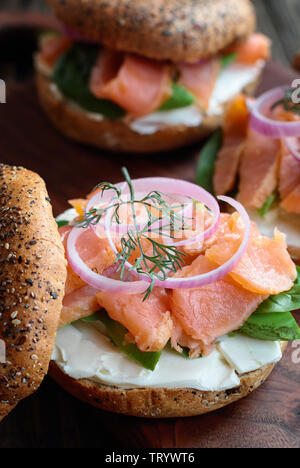 Lox - Tout ce bagel avec du saumon fumé, Épinards, oignons rouges, avocat et fromage à la crème sur une table en bois rustique. Focus sélectif. Banque D'Images