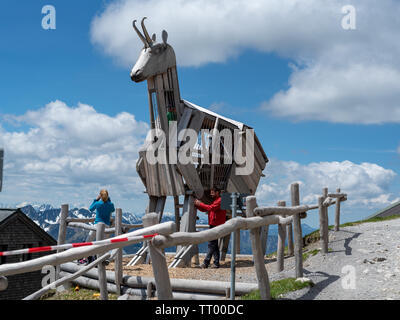 Orange, Bavière, Allemagne - 1 juin 2019. Jouer les touristes autour de la grande sculpture de chèvre de montagne en bois au sommet de mont Wendelstein Banque D'Images