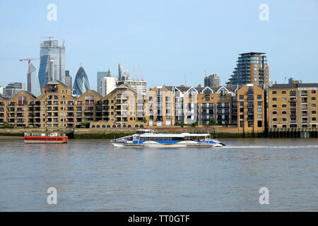 Un Thames Clipper sur la Tamise près de Wapping riverside appartements avec vue sur la ville de Londres Londres Angleterre Royaume-uni gratte-ciel Banque D'Images