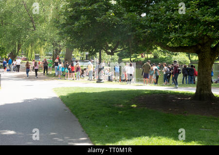 Les gens de tous les groupes d'âge bénéficiant d'un bel après-midi de printemps avec des adultes et des enfants par la Lagune dans le Jardin Public de Boston Massachusetts Banque D'Images
