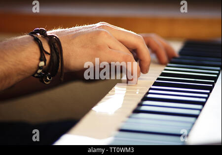 Sur l'instrument à clavier, ce qui est éclairé par la faible lumière du soleil, les mains des hommes appuyez sur les touches, jouer une mélodie Banque D'Images