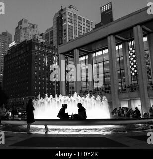 New York - 10 juin 2016 : Deux femmes assises en face de la fontaine au Lincoln Center de nuit avec fontaine lumineuse crée son profil. La SLA Banque D'Images