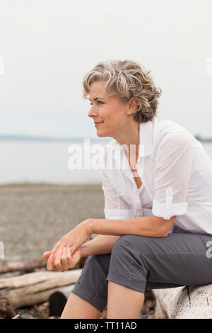 Beau, heureux, en bonne santé, d'âge moyen, smiling mature woman sitting outdoors on beach Banque D'Images