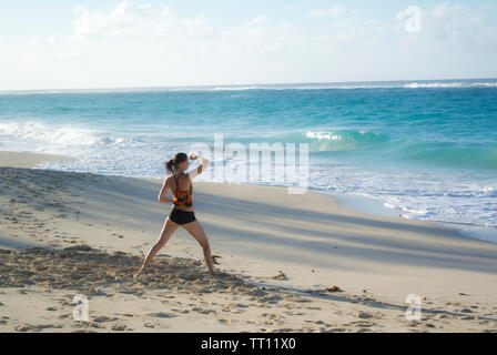 Femme pratiquant le tai-chi sur la plage Banque D'Images