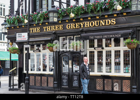 Un homme habillé en passant solitaire passe devant les trois lévriers public house in Greek Street, Soho, Londres Banque D'Images