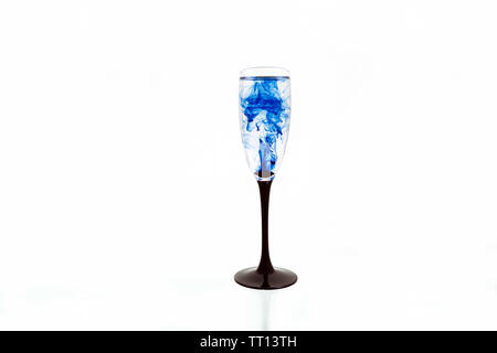 Verre de vin sur fond blanc avec des peintures de couleur bleue à l'intérieur. Fougere pour champagne avec de la fumée et les ensemencer. Banque D'Images