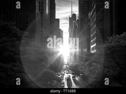 Soleil noir et blanc brillant entre la ligne d'horizon bâtiments le long de la 42ème rue à Midtown Manhattan, New York City Banque D'Images