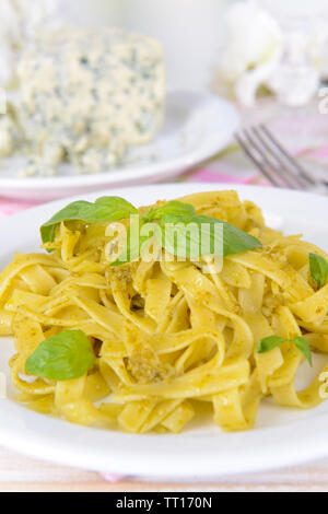 Délicieux plats de pâtes au pesto sur la plaque sur la table sur un fond clair Banque D'Images